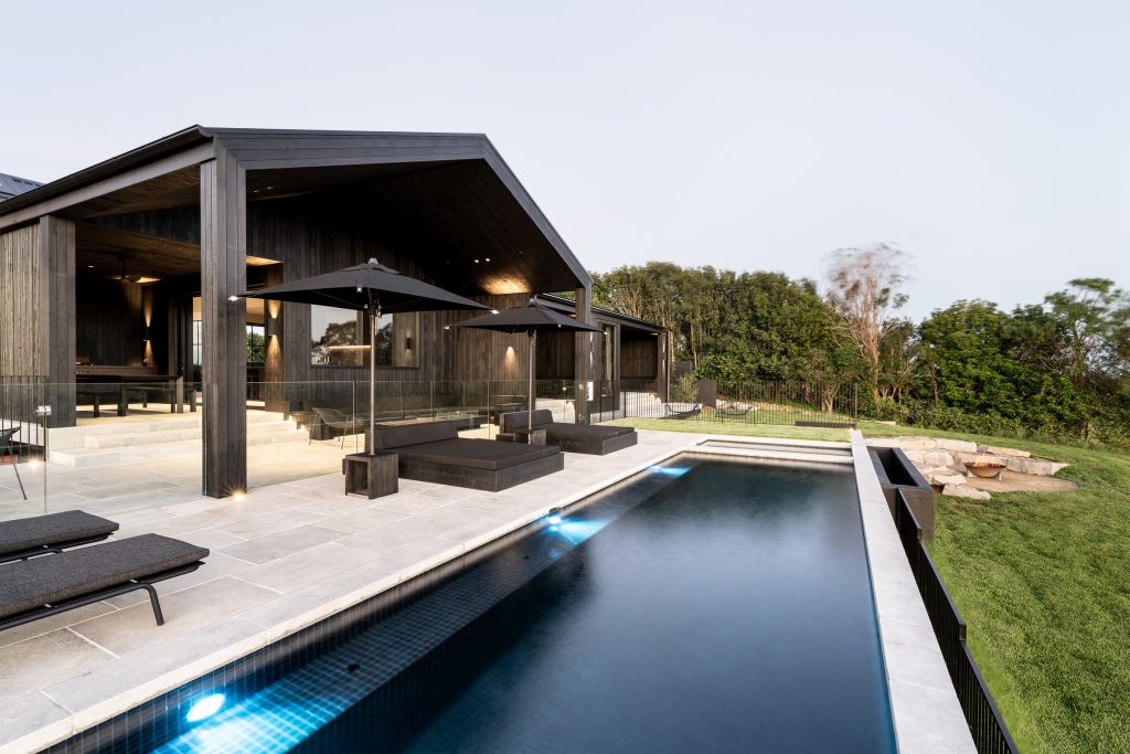 Nox Byron Bay exterior with black cladding, pool with black tiles, black daybeds and black umbrellas