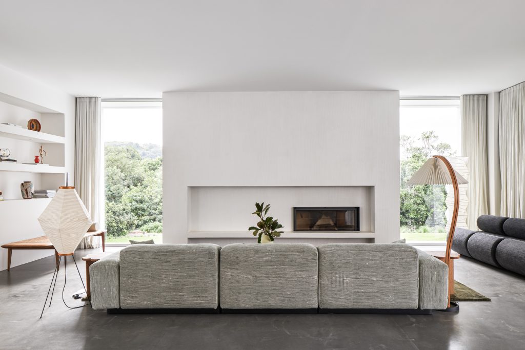 Currawong House living room with two large vertical windows and fireplace